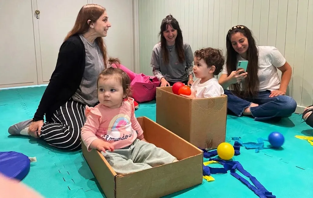Bebes jugando adentro de cajas con pelotitas de colores y terapeutas en Brainbow